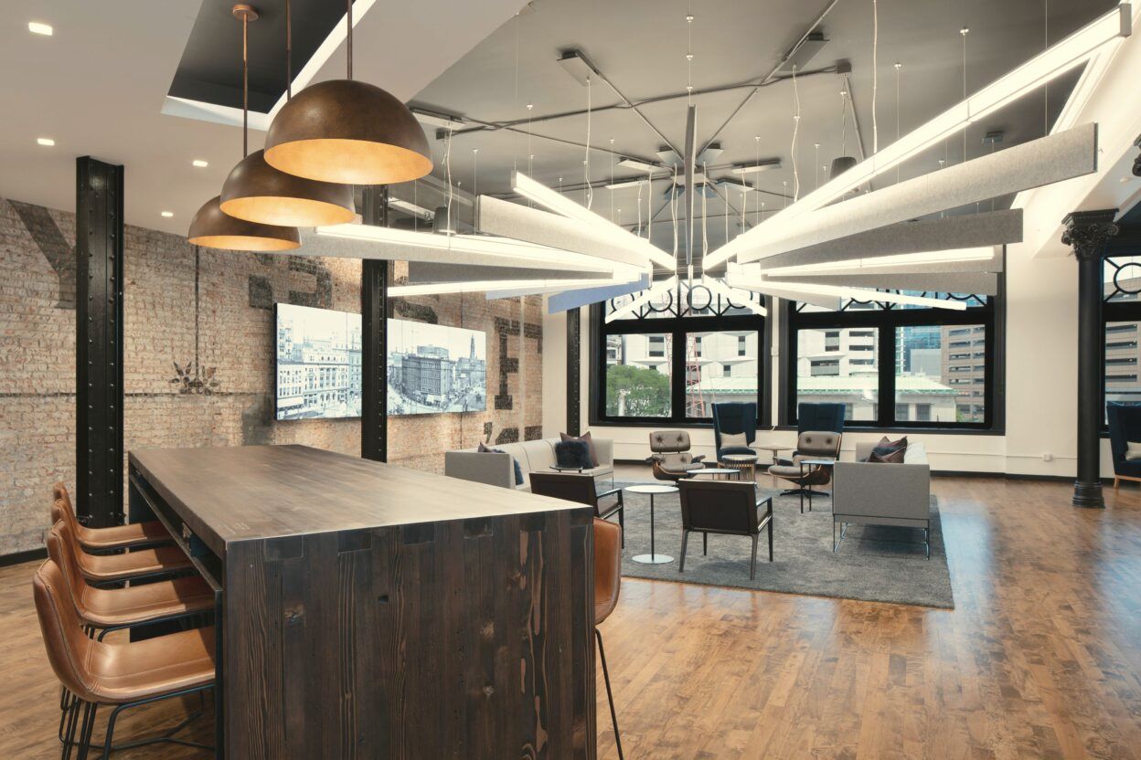 A warmly lit lounge with pendant lights and wood floors